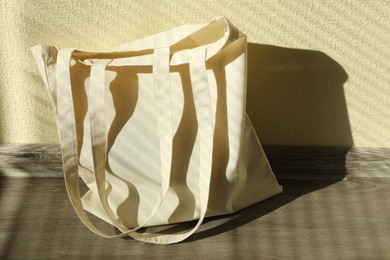 Photo of One eco bag on floor near beige wall. Mockup for design