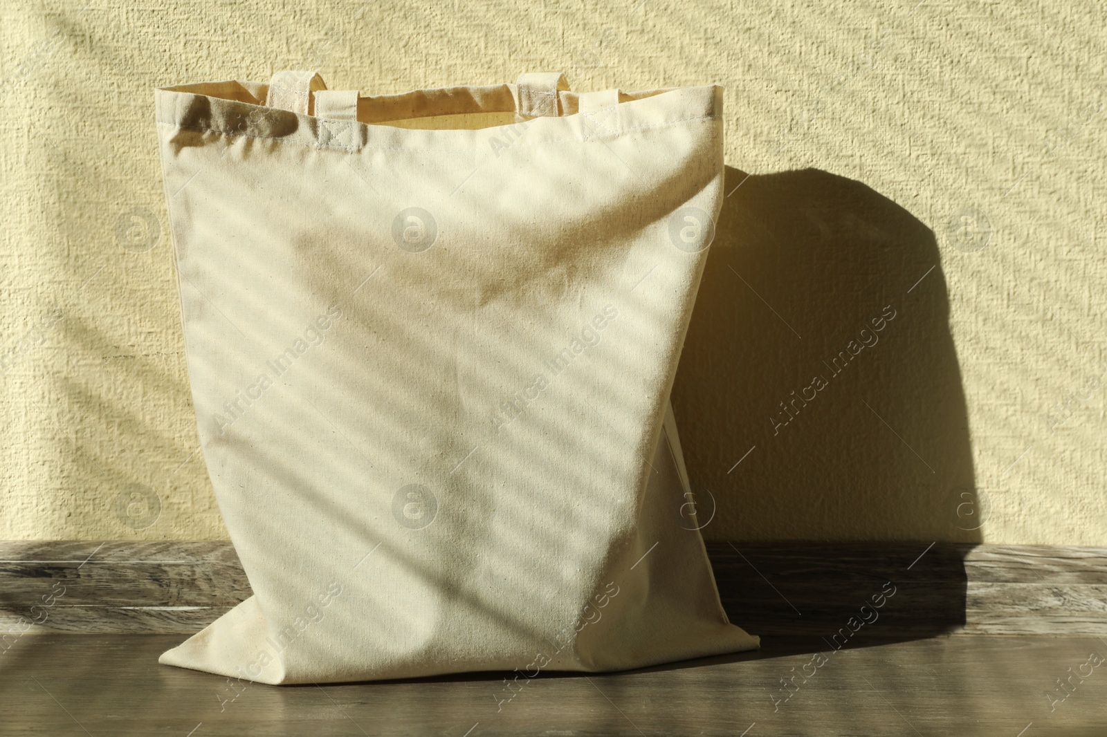 Photo of One eco bag on floor near beige wall. Mockup for design