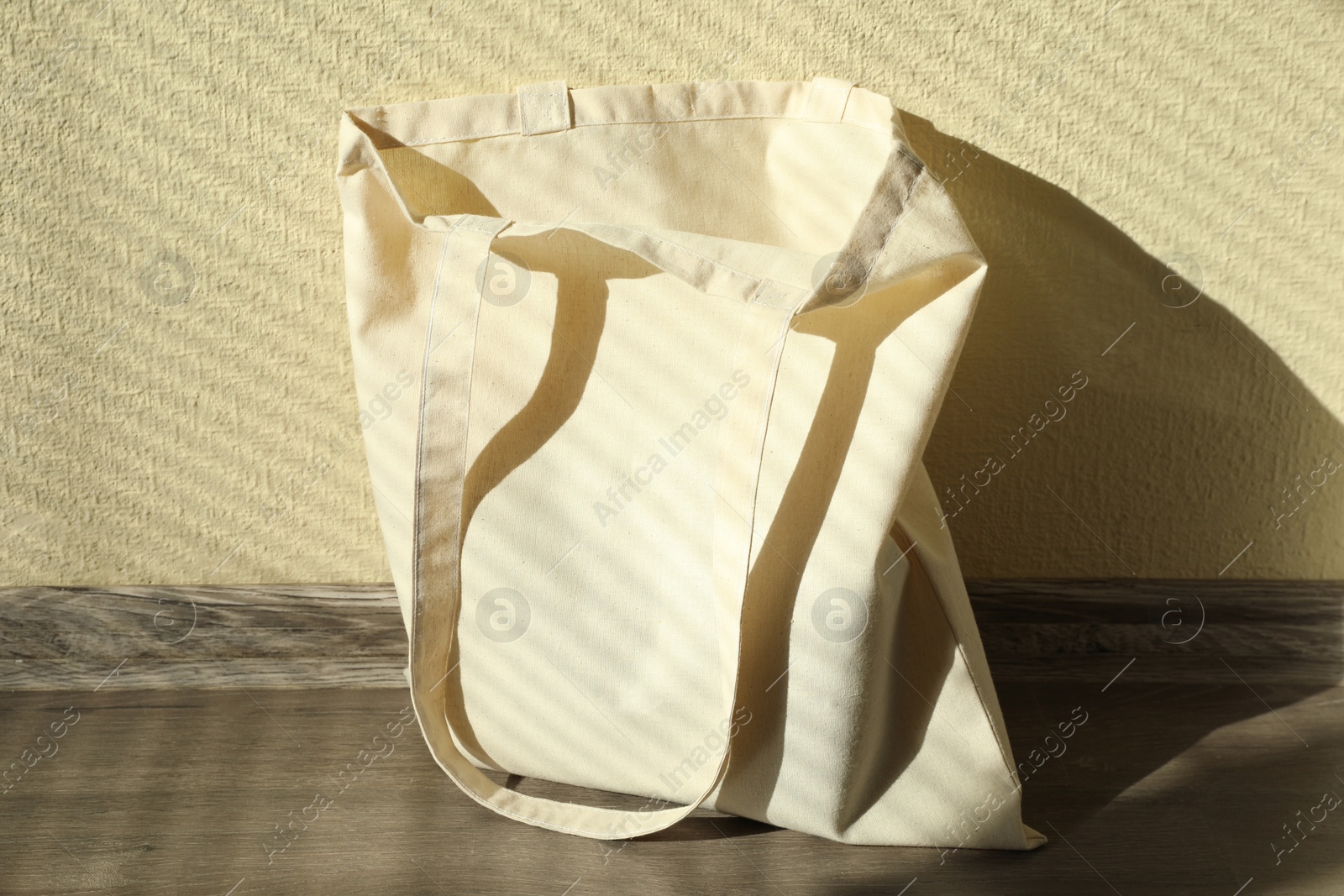 Photo of One eco bag on floor near beige wall. Mockup for design