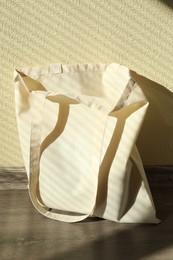 Photo of One eco bag on floor near beige wall. Mockup for design