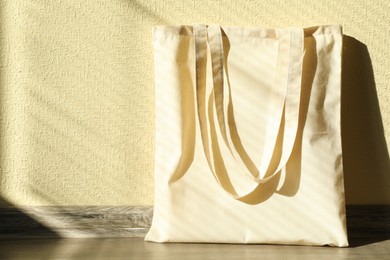 Photo of One eco bag on floor near beige wall. Mockup for design