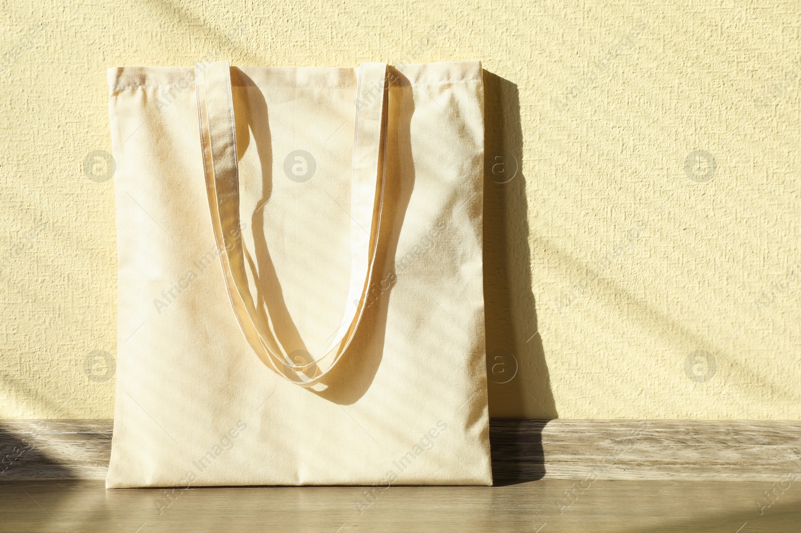 Photo of One eco bag on floor near beige wall. Mockup for design