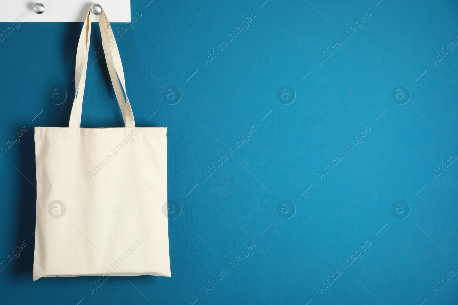 Photo of One eco bag hanging on blue wall. Mockup for design