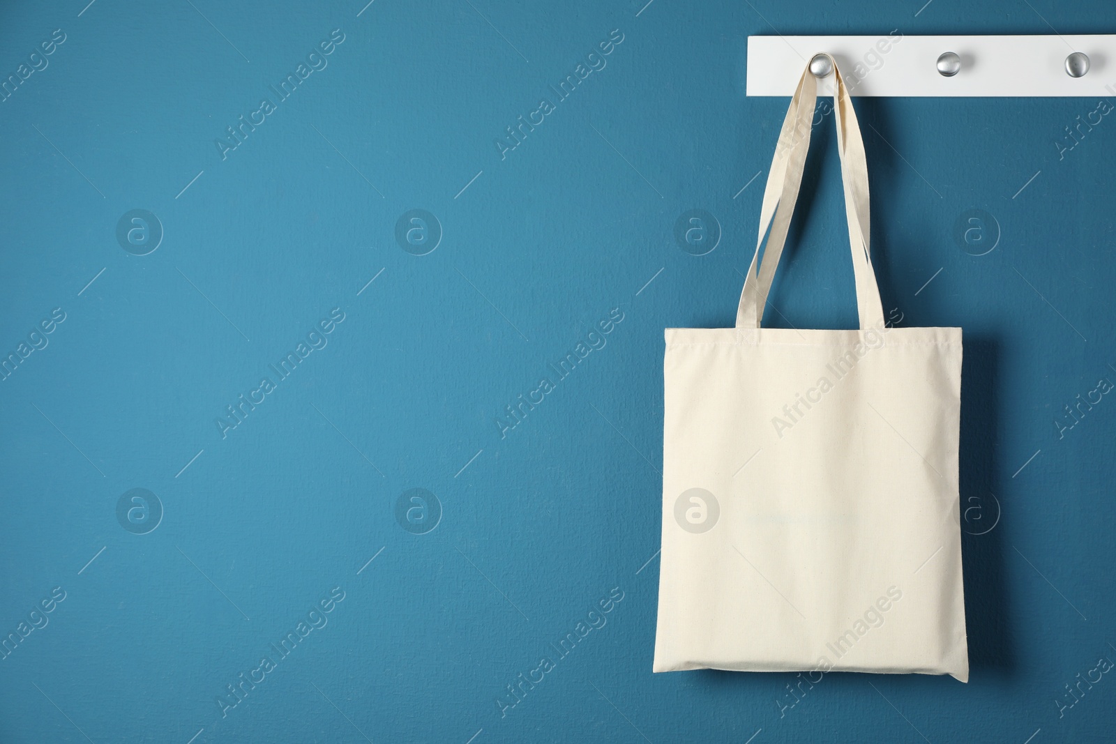 Photo of One eco bag hanging on blue wall. Mockup for design