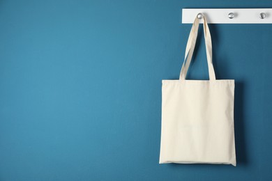 Photo of One eco bag hanging on blue wall. Mockup for design