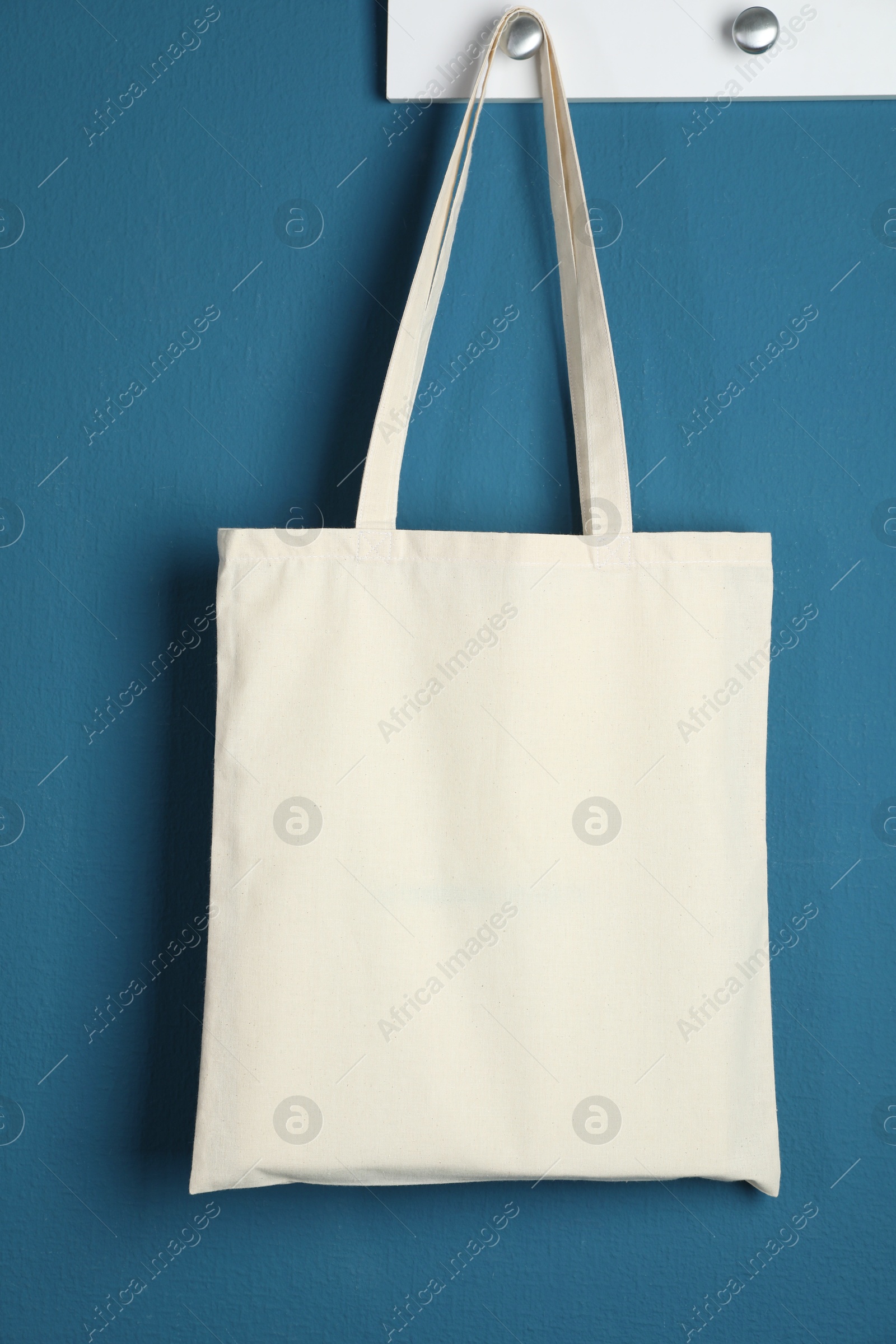 Photo of One eco bag hanging on blue wall. Mockup for design