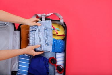 Photo of Traveler packing suitcase on red background, top view. Space for text