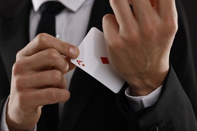 Photo of Illusionist taking playing card out of sleeve, closeup