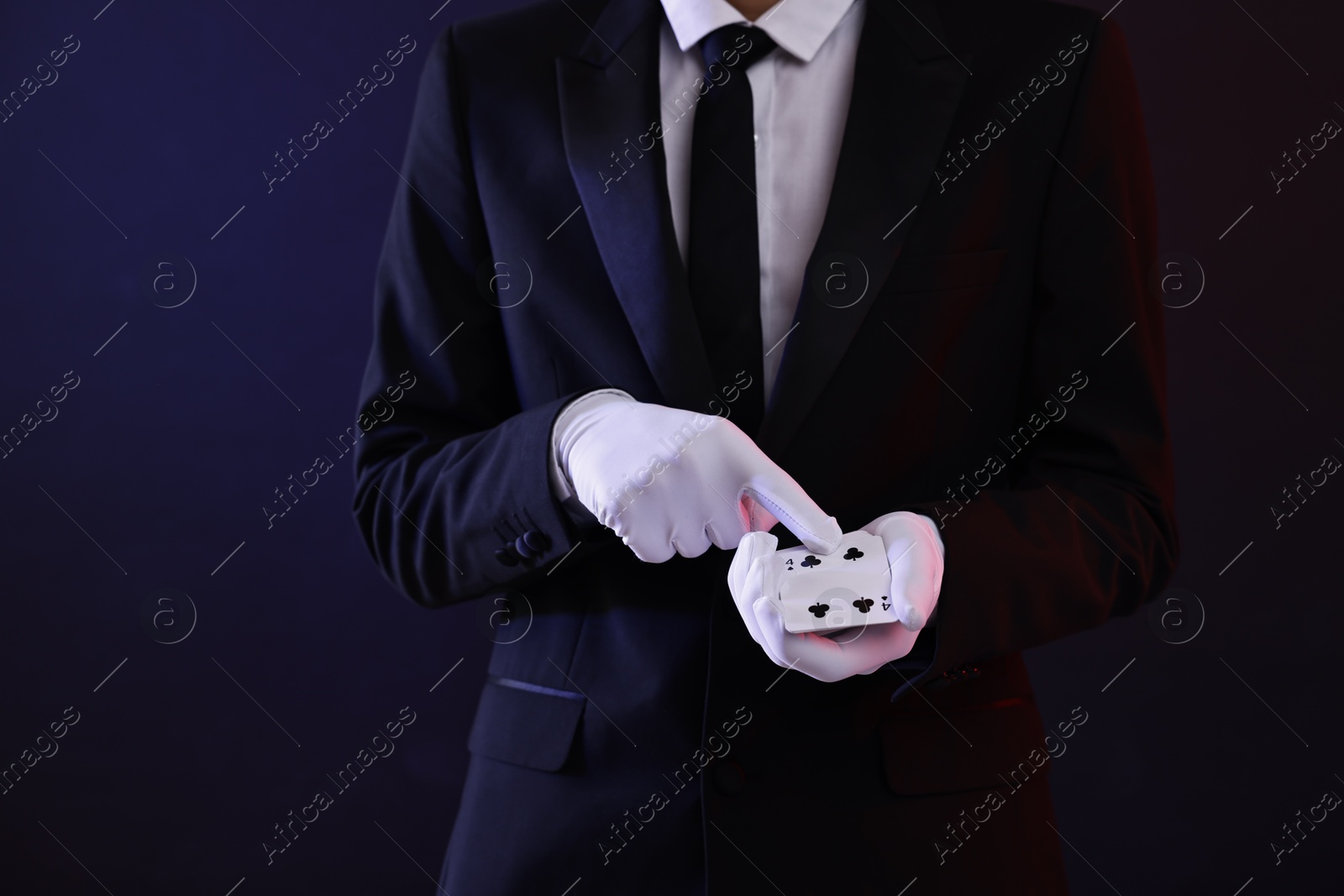 Photo of Illusionist with playing cards on dark background, closeup. Space for text