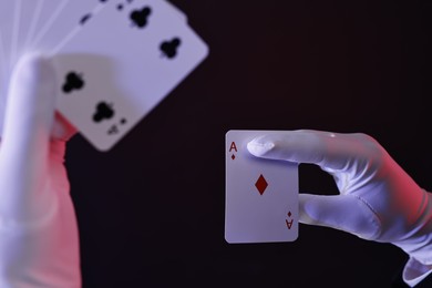 Illusionist with playing cards on dark background, closeup