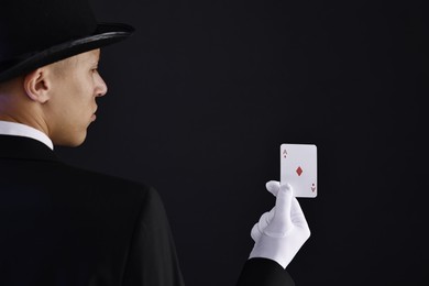 Photo of Illusionist with playing card on black background