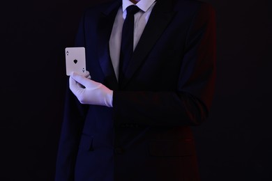 Photo of Illusionist showing playing card on black background, closeup