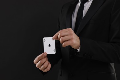 Photo of Illusionist showing playing card on black background, closeup. Space for text