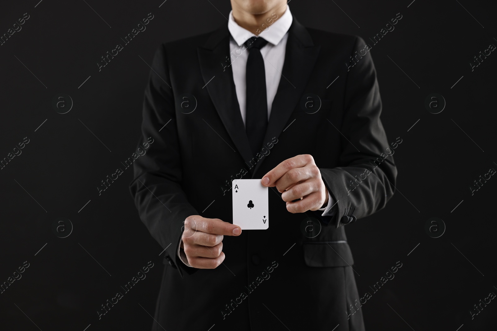 Photo of Illusionist showing playing card on black background, closeup