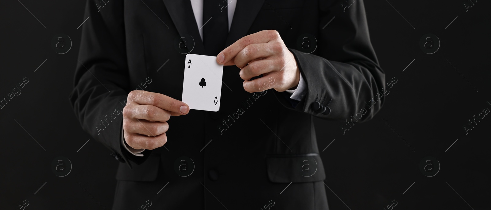 Photo of Illusionist showing playing card on black background, closeup