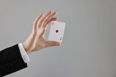 Photo of Illusionist showing playing card on grey background, closeup. Space for text