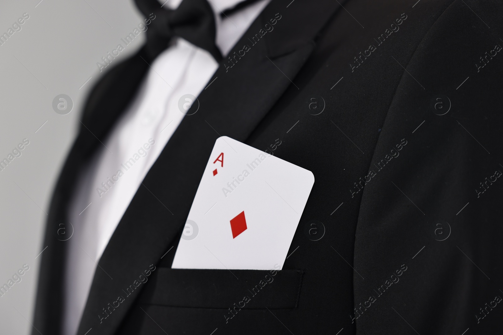 Photo of Illusionist with playing card in his pocket on grey background, closeup