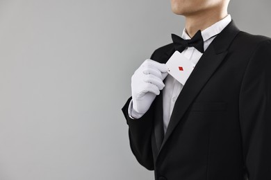 Photo of Illusionist hiding playing card behind jacket lapel on grey background, closeup. Space for text