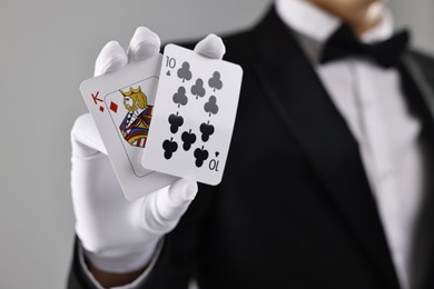 Photo of Illusionist showing playing cards on grey background, closeup