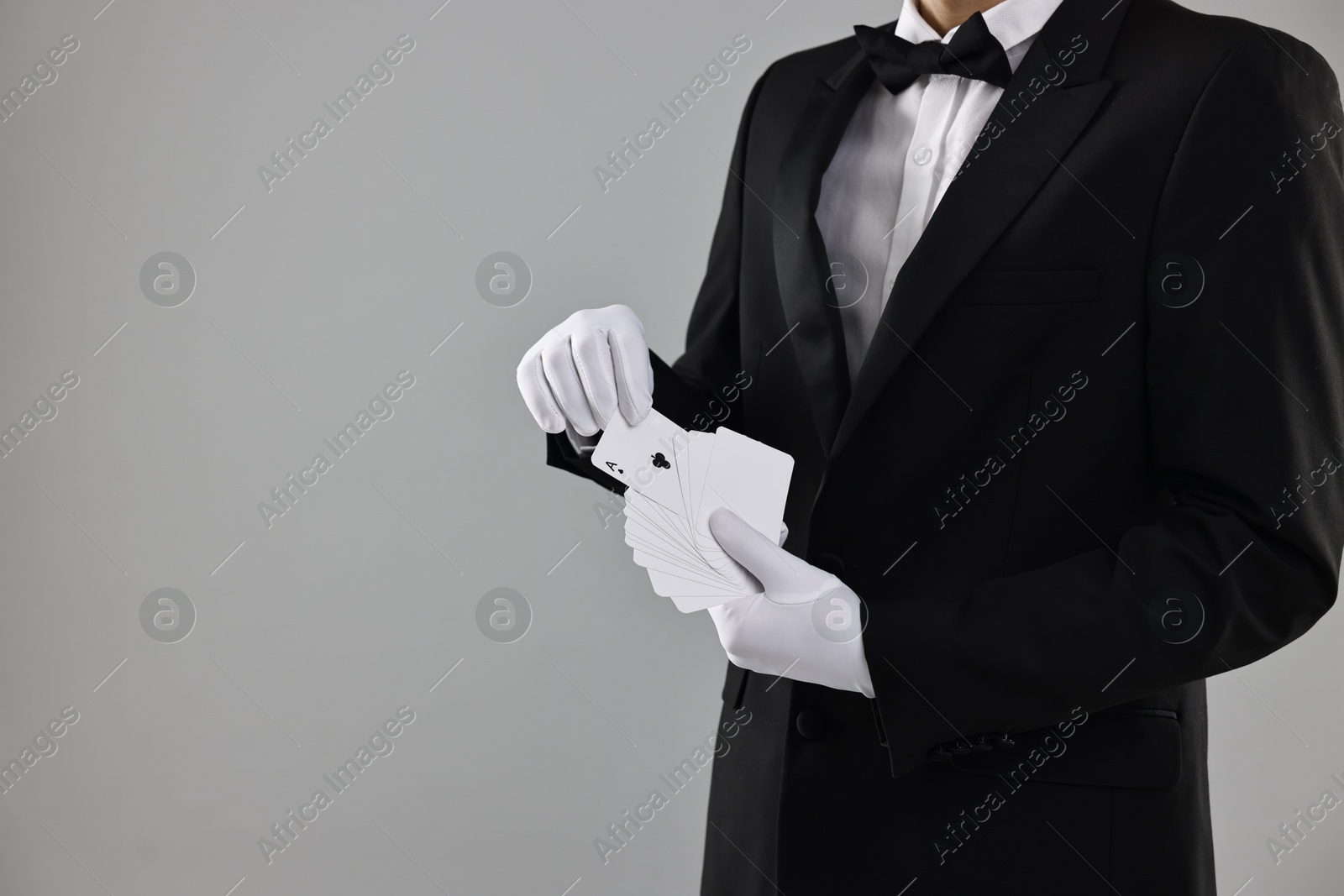 Photo of Illusionist taking one playing card from deck on grey background, closeup. Space for text