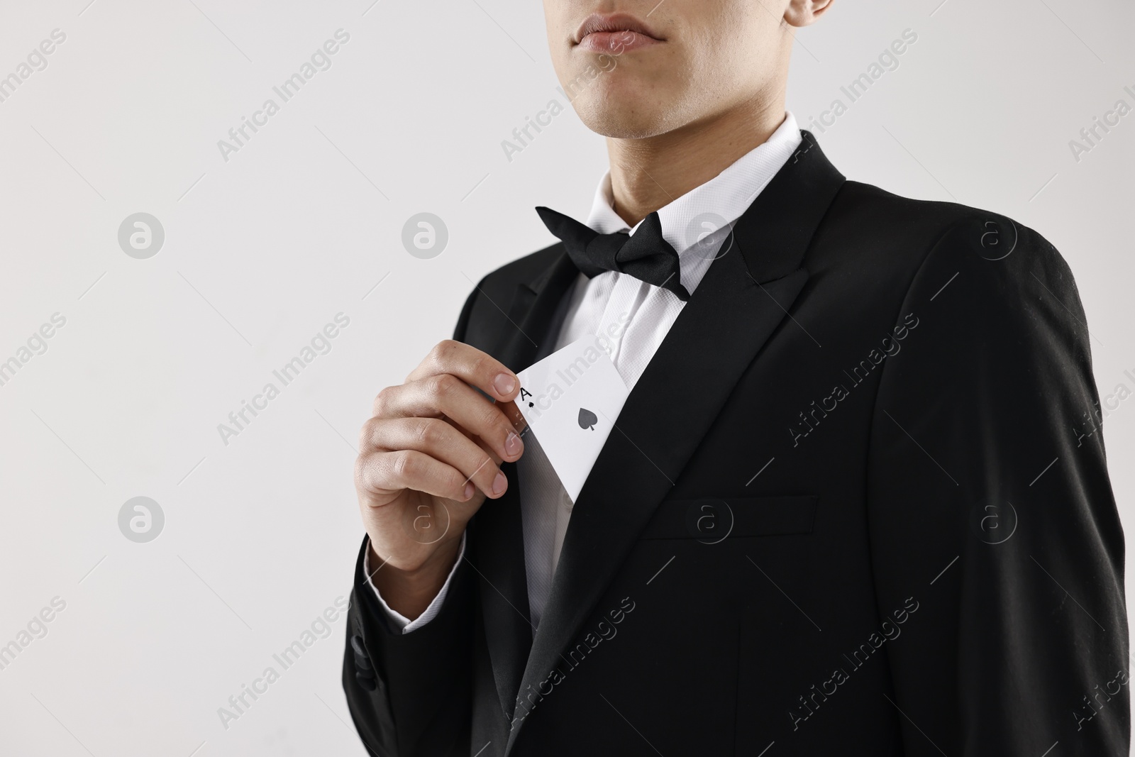 Photo of Illusionist hiding playing card behind jacket lapel on white background, closeup. Space for text