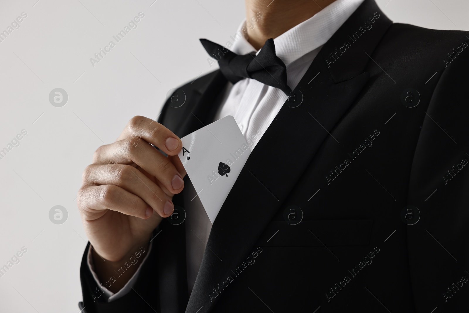 Photo of Illusionist hiding playing card behind jacket lapel on white background, closeup