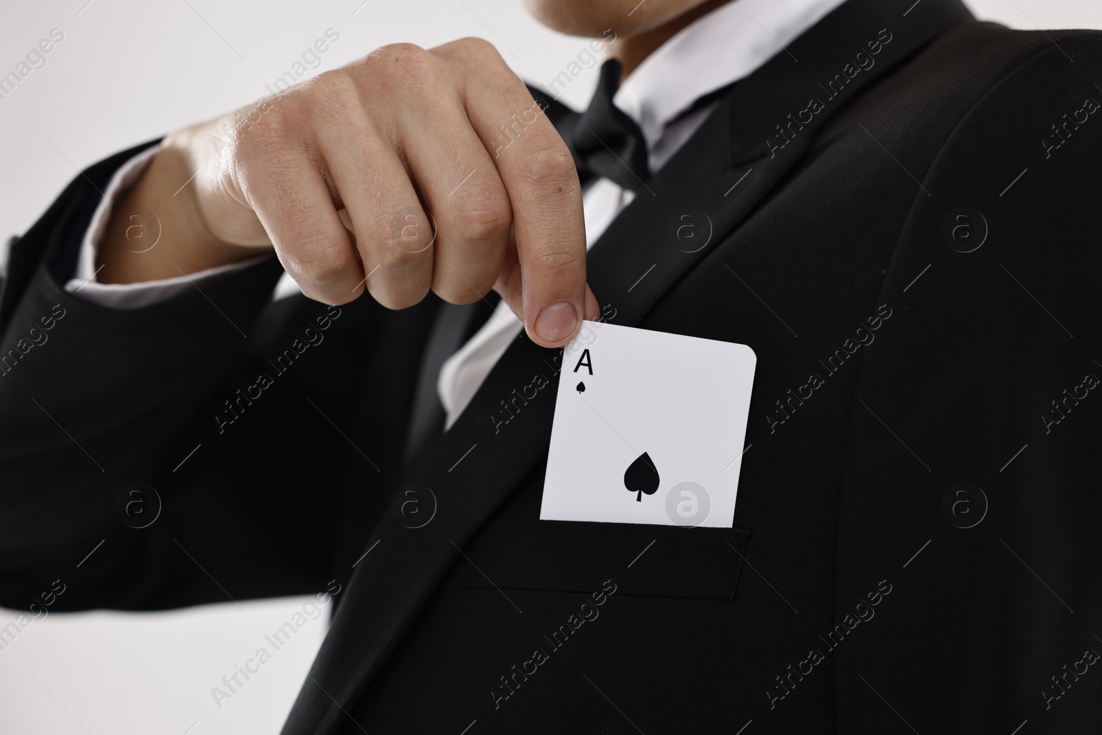 Photo of Illusionist taking playing card out of pocket on white background, closeup