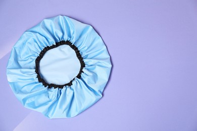 Photo of One shower cap on lilac background, top view. Space for text