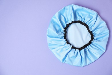 Photo of One shower cap on lilac background, top view. Space for text