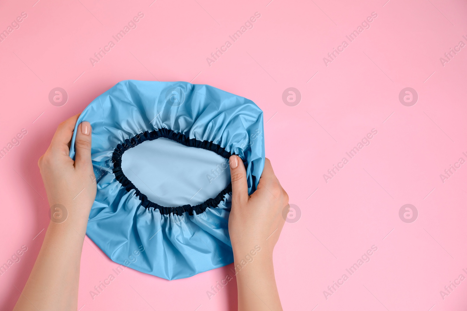 Photo of Woman with shower cap on pink background, top view. Space for text