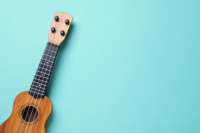 Photo of One ukulele on turquoise background, top view. Space for text