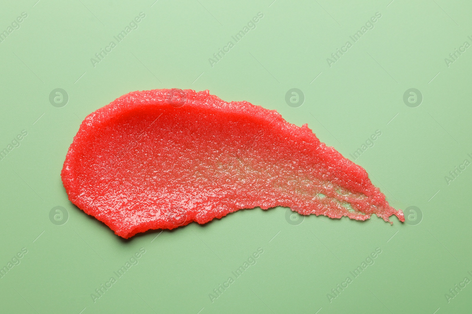 Photo of Smear of body scrub on light green background, top view