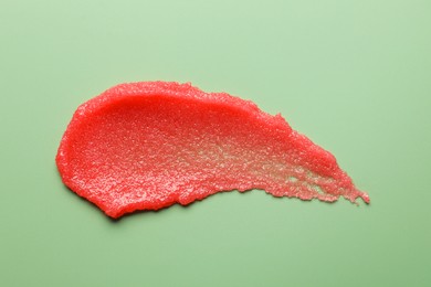 Photo of Smear of body scrub on light green background, top view