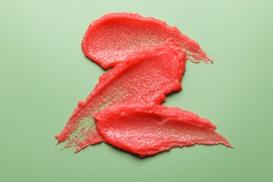 Photo of Smears of body scrub on light green background, top view