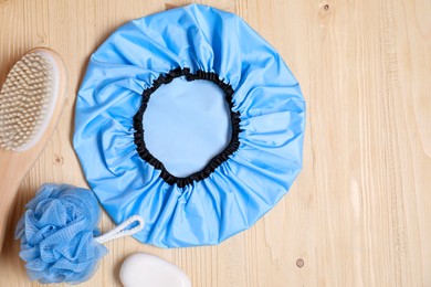 Photo of Shower cap and bath accessories on wooden background, flat lay. Space for text