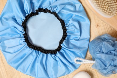 Photo of Shower cap and bath accessories on wooden background, flat lay