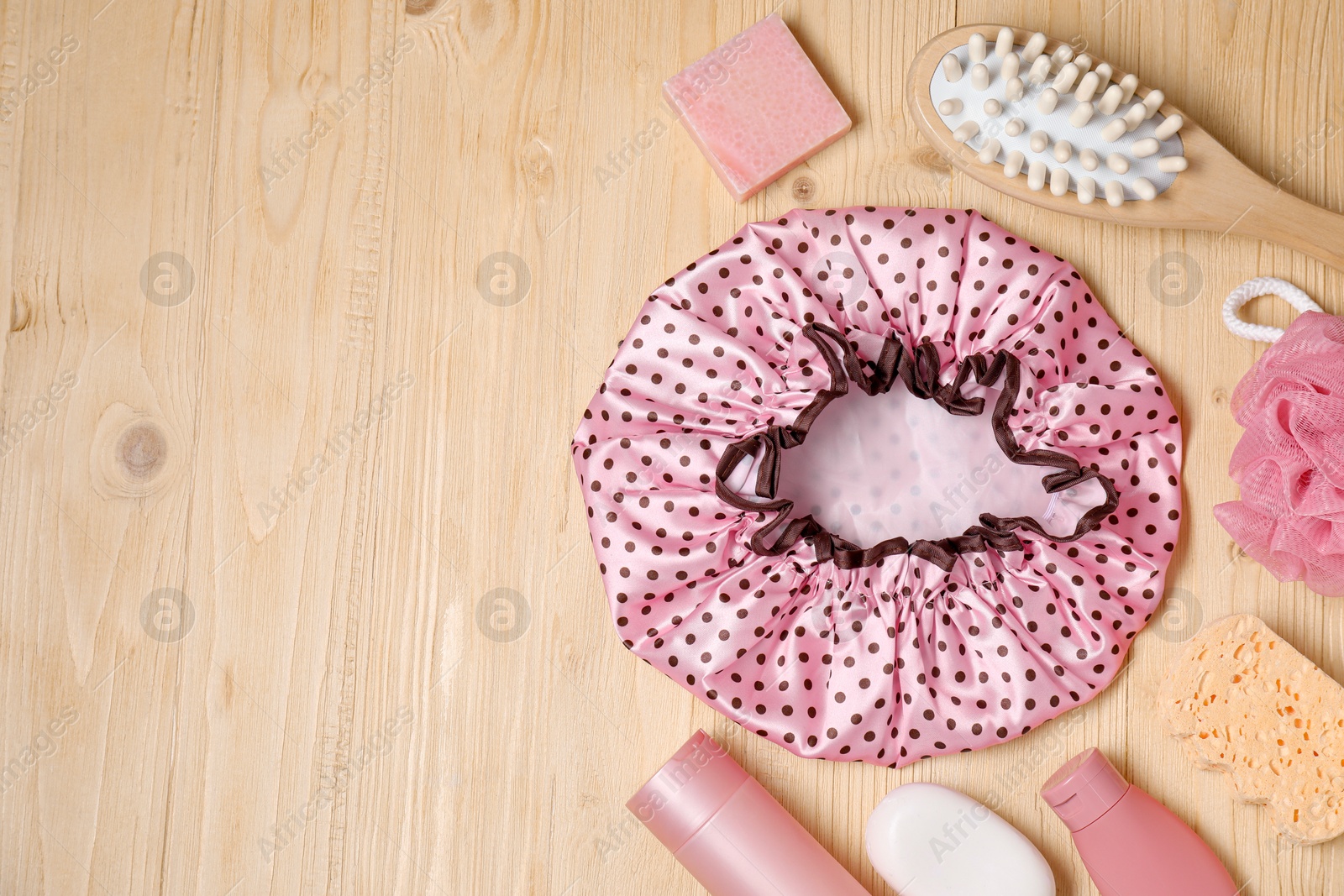 Photo of Shower cap and bath accessories on wooden background, flat lay. Space for text