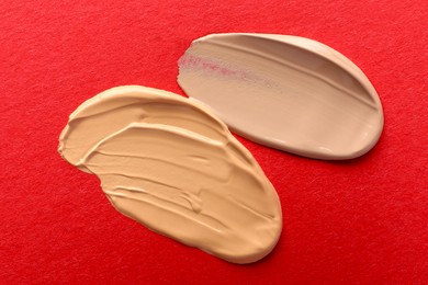 Photo of Samples of different foundations on red background, closeup