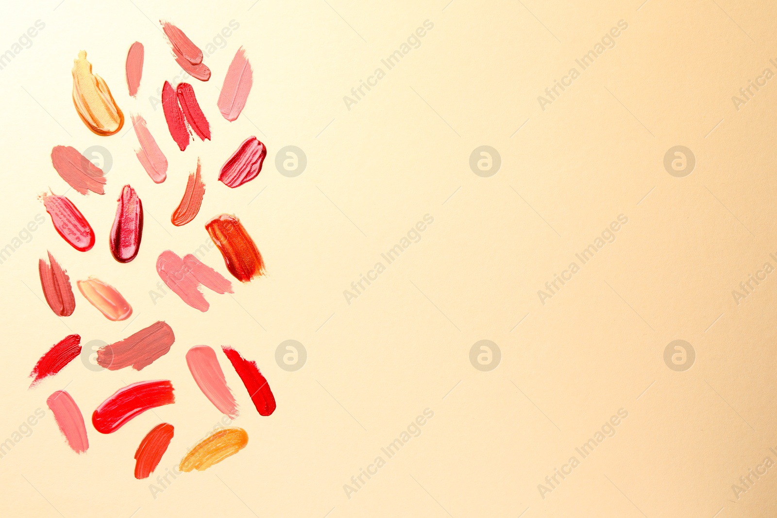 Photo of Samples of different lip products on beige background, top view. Space for text