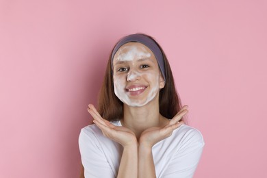 Photo of Teenage girl with cleansing foam on her face against pink background. Acne treatment