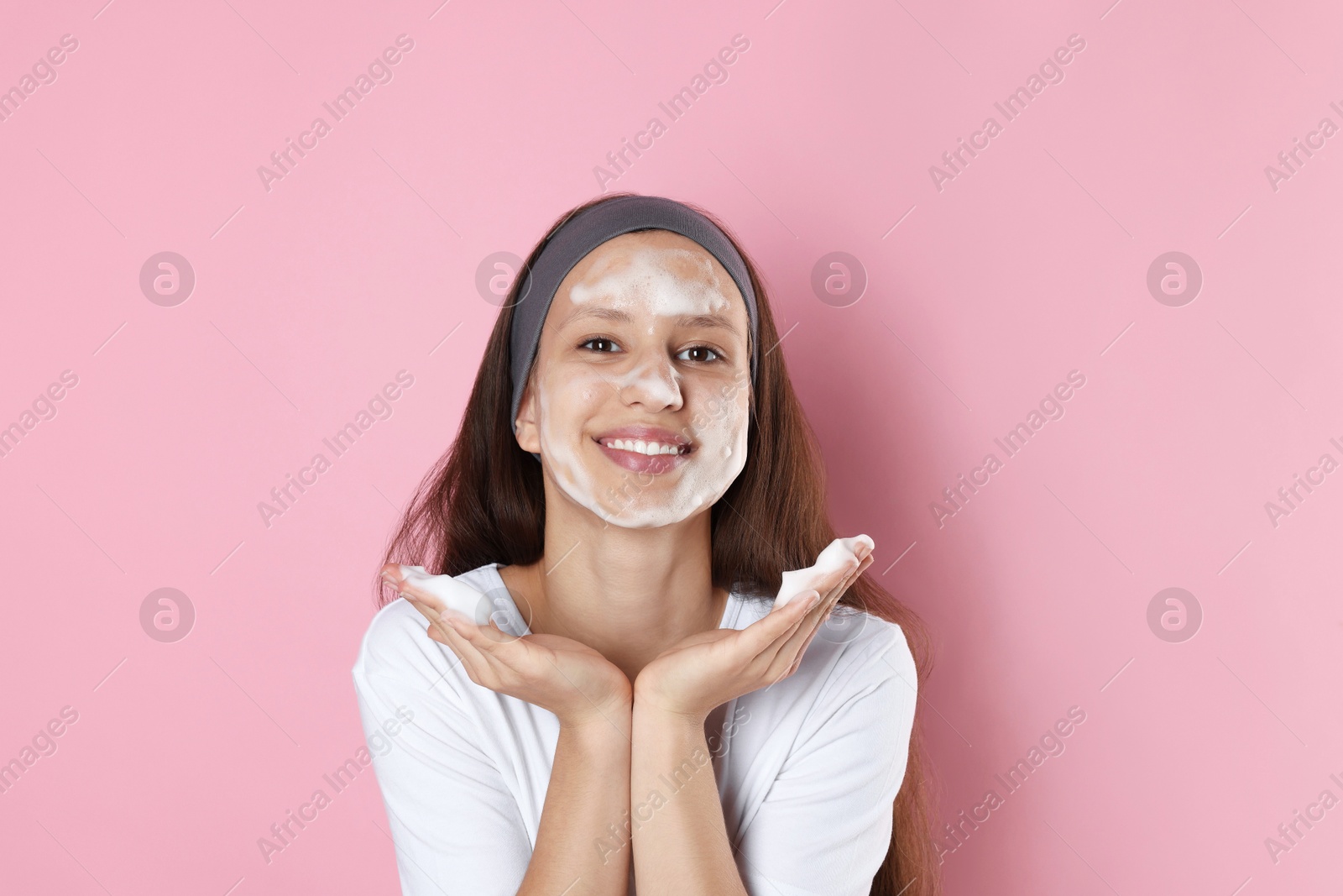 Photo of Teenage girl with cleansing foam on her face against pink background. Acne treatment