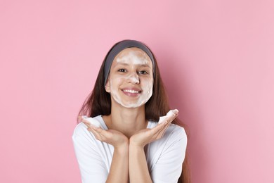 Photo of Teenage girl with cleansing foam on her face against pink background. Acne treatment