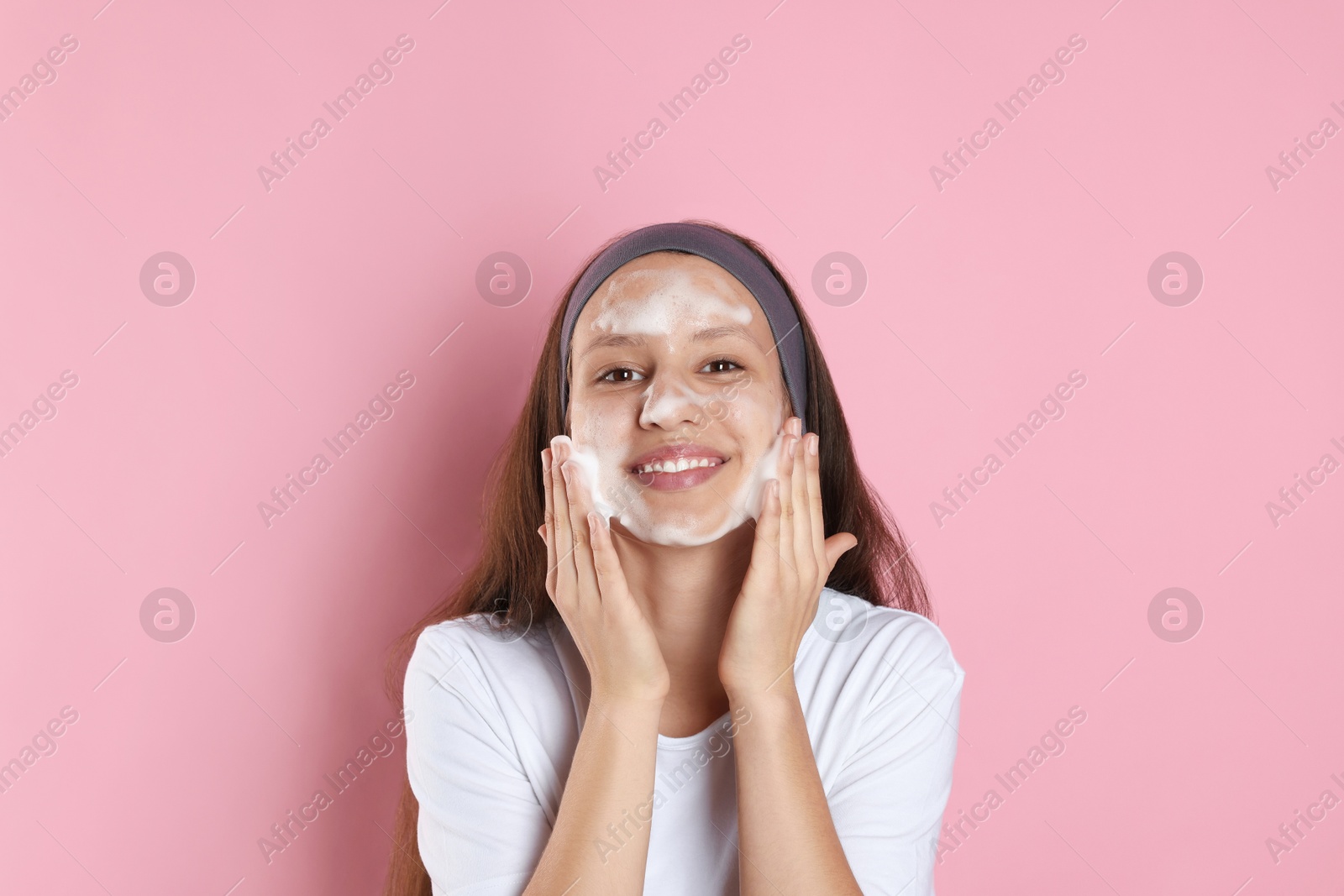 Photo of Teenage girl with cleansing foam on her face against pink background. Acne treatment