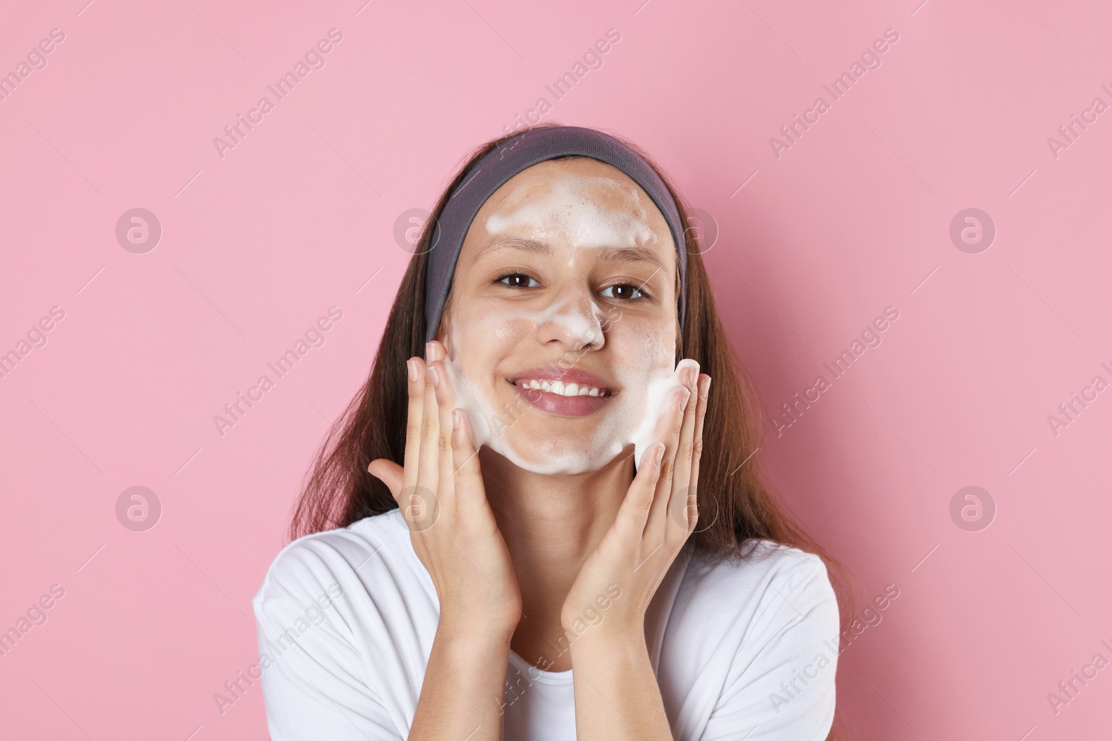 Photo of Teenage girl with cleansing foam on her face against pink background. Acne treatment