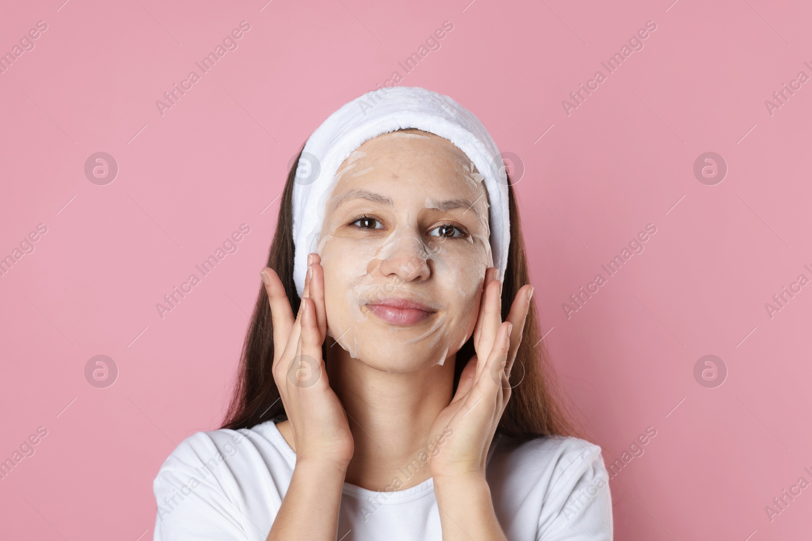 Photo of Teenage girl with sheet facial mask on pink background. Acne treatment