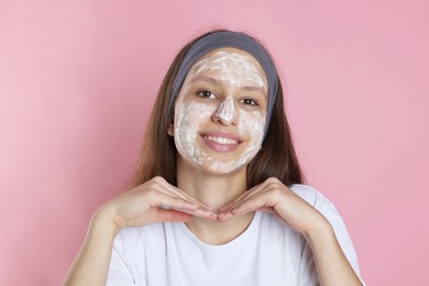 Photo of Teenage girl with cream on her face against pink background. Acne treatment