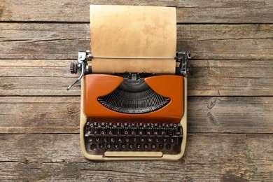 Photo of Vintage typewriter with sheet of parchment paper on wooden table, top view