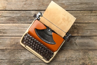 Photo of Vintage typewriter with sheet of parchment paper on wooden table, top view