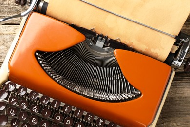 Photo of Vintage typewriter with sheet of parchment paper on wooden table, top view