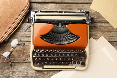 Photo of Vintage typewriter, bag, glasses, envelopes and sheets of paper on wooden table, flat lay